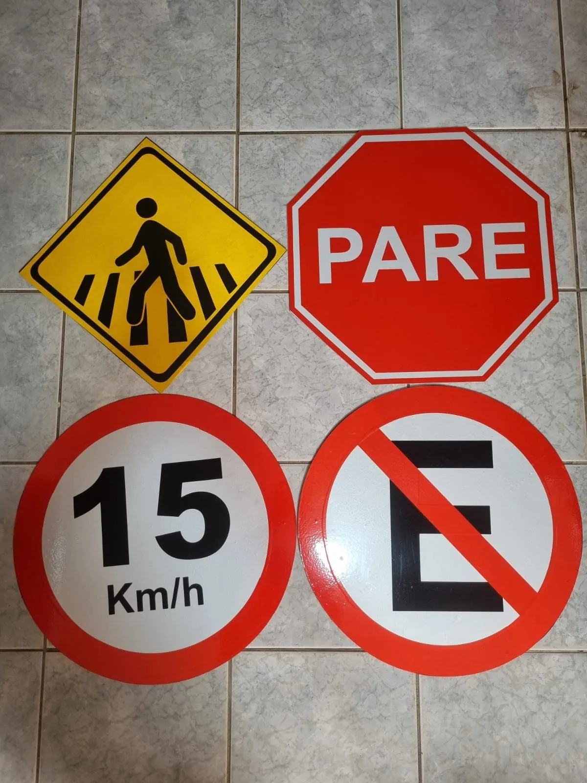 Placas de regulamentação fabricadas pela Belplac em Recife: PARE (R-1) octogonal, velocidade máxima 15 km/h (R-19), proibido estacionar (R-6a) e travessia de pedestres