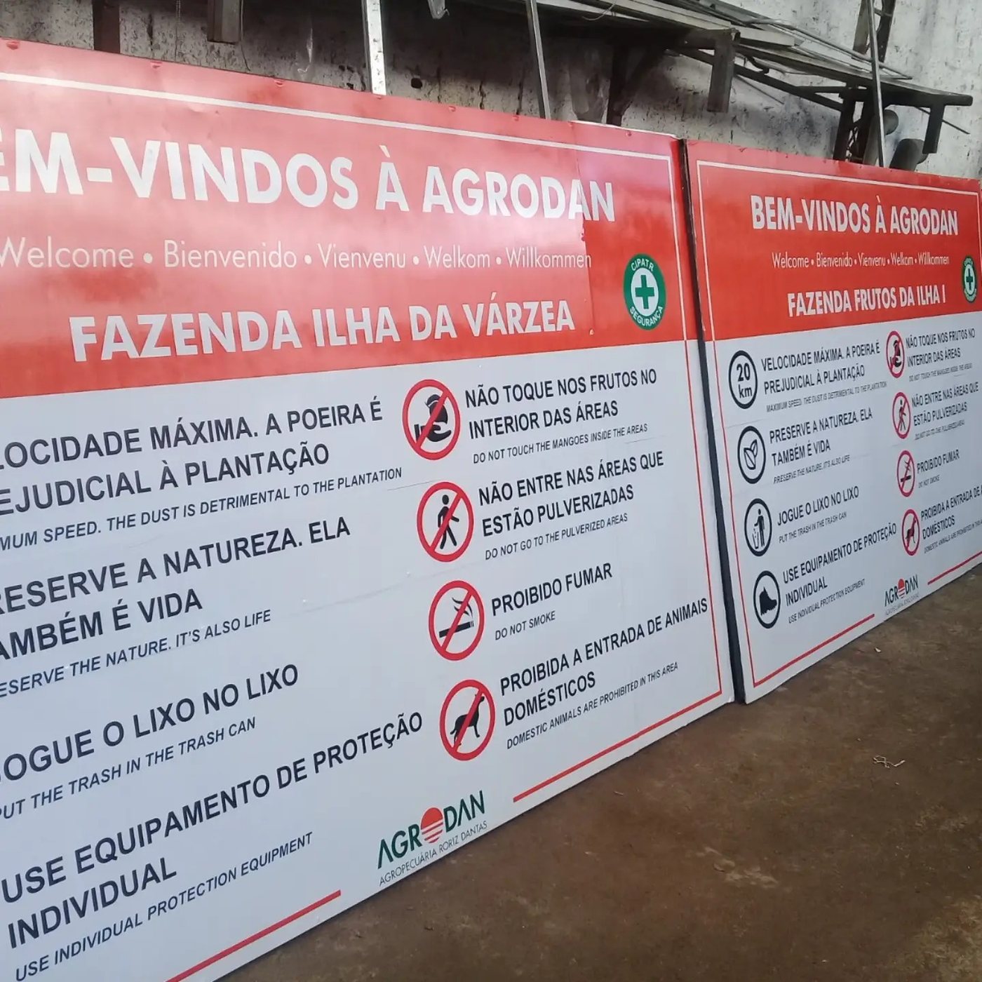 Placas de boas-vindas e regras de segurança para fazenda, em português e inglês